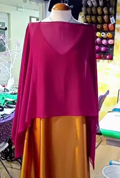 Conjunto de festa com capa em chiffon magenta e vestido acetinado mostarda, em manequim no ateliê Mil Agulhas.