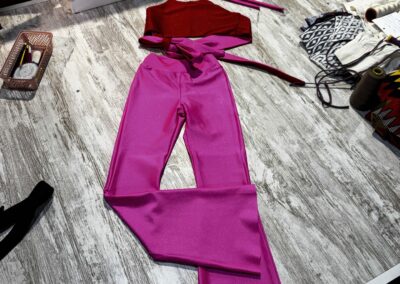Conjunto de dança de duas peças feito à medida, com top frente-única em vermelho e rosa-choque e calças à boca-de-sino, em tecido brilhante.